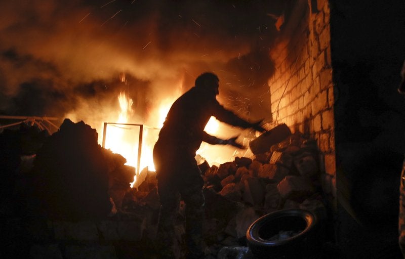 Una persona intenta sacar las ruedas de una tienda de repuestos tras bombardeo de la artillería de Azerbaiyán durante un enfrentamiento en Stepanakert.