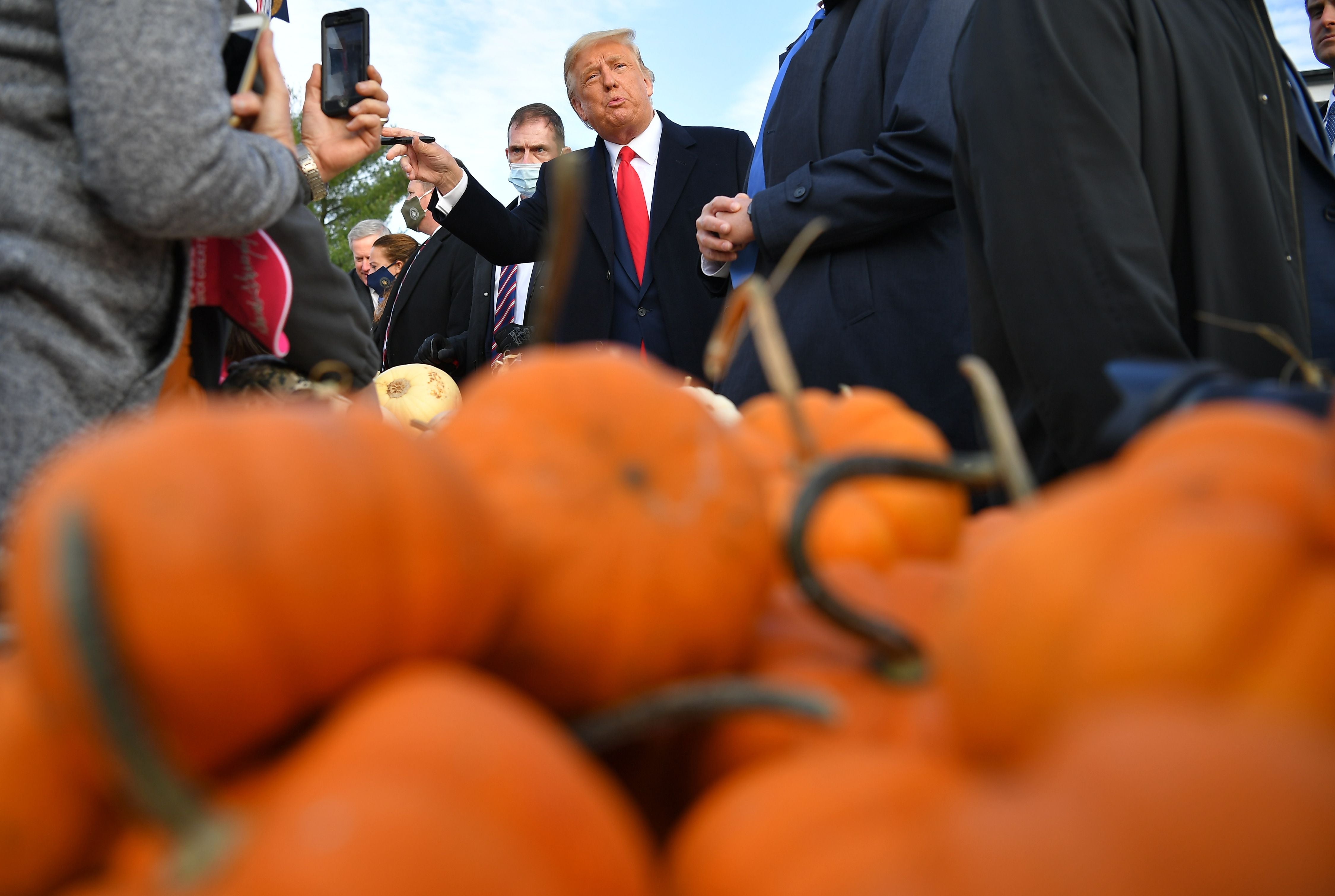 US President Donald Trump(C) signs hats as he meets with people at Treworgy Orchards during a campaign stop in Levant, Maine on October 25, 2020. - In a single day, he covered more than 3,000 kilometers (1,800 miles) aboard Air Force One, hitting three different campaign rallies from the country's south to the midwest. And Donald Trump has shown his willingness to keep up the frenetic pace he set on October 24, 2020 all the way until the November 3 election. (Photo by MANDEL NGAN / AFP) (Photo by MANDEL NGAN/AFP via Getty Images)