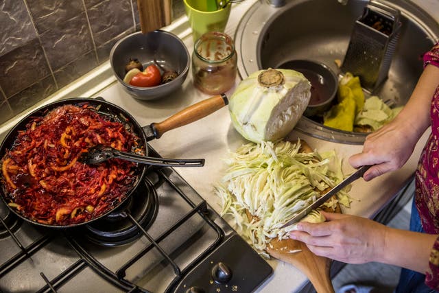 Oksana Chadaieva, 50, chops a cabbage in her kitchen as she prepares borscht