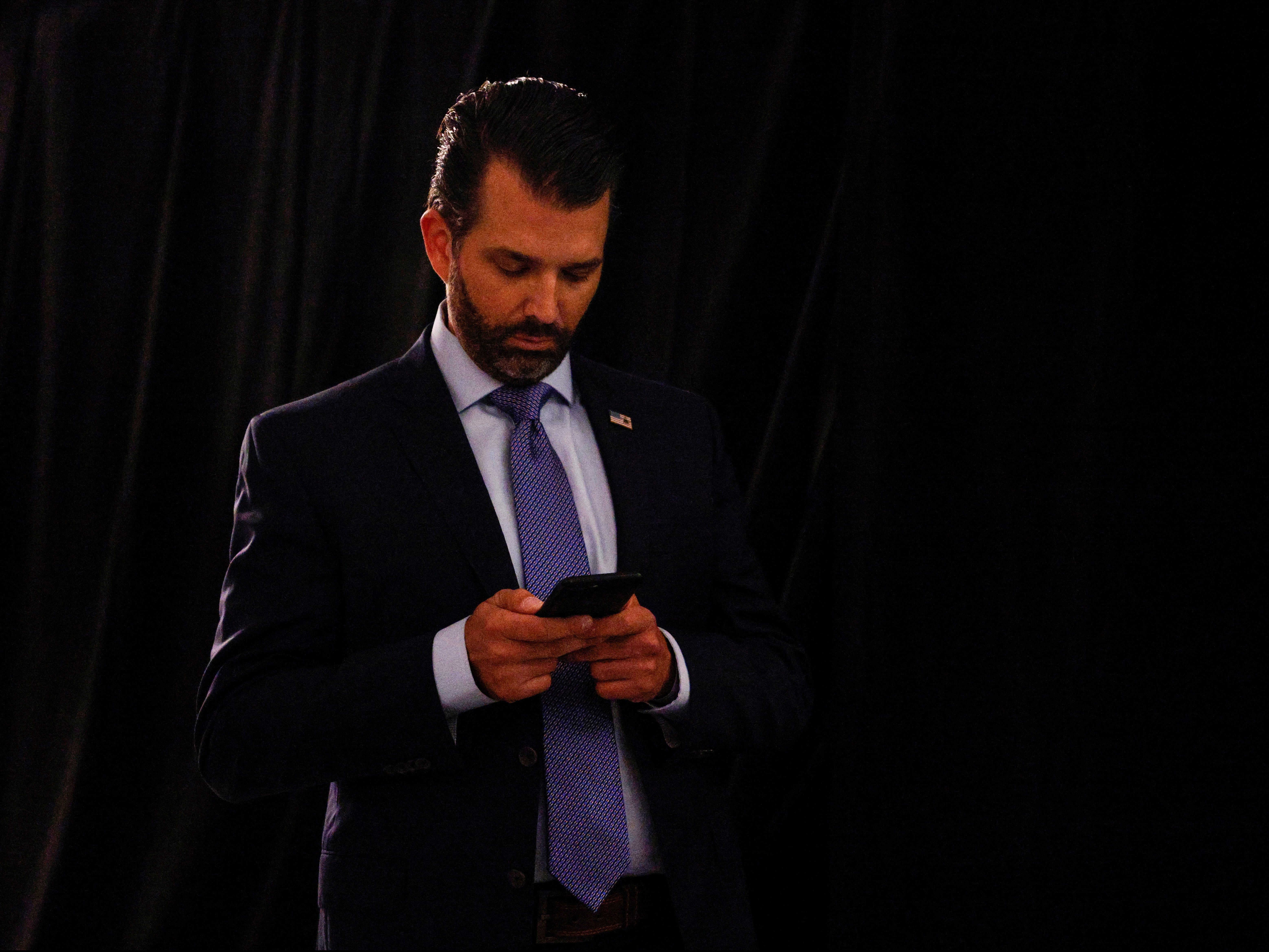 Donald Trump Jr uses his phone as he leaves after the first 2020 presidential campaign debate
