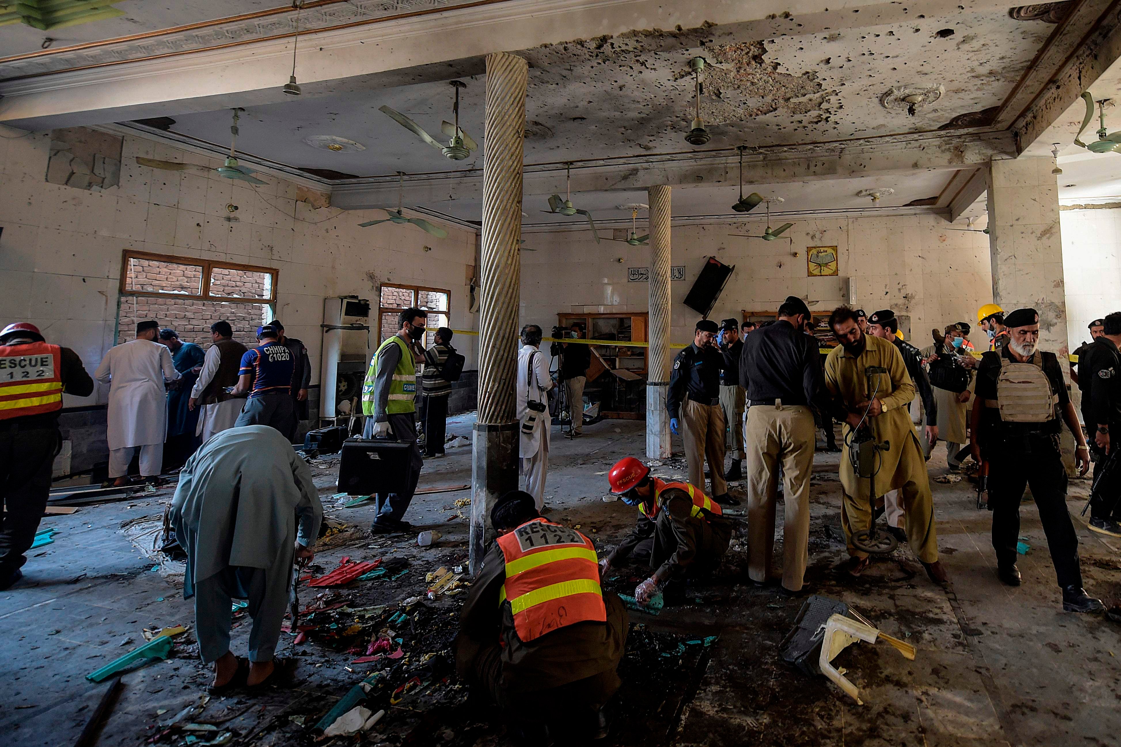 Security officials examine the site of a blast at a religious school in Peshawar on Tuesday morning