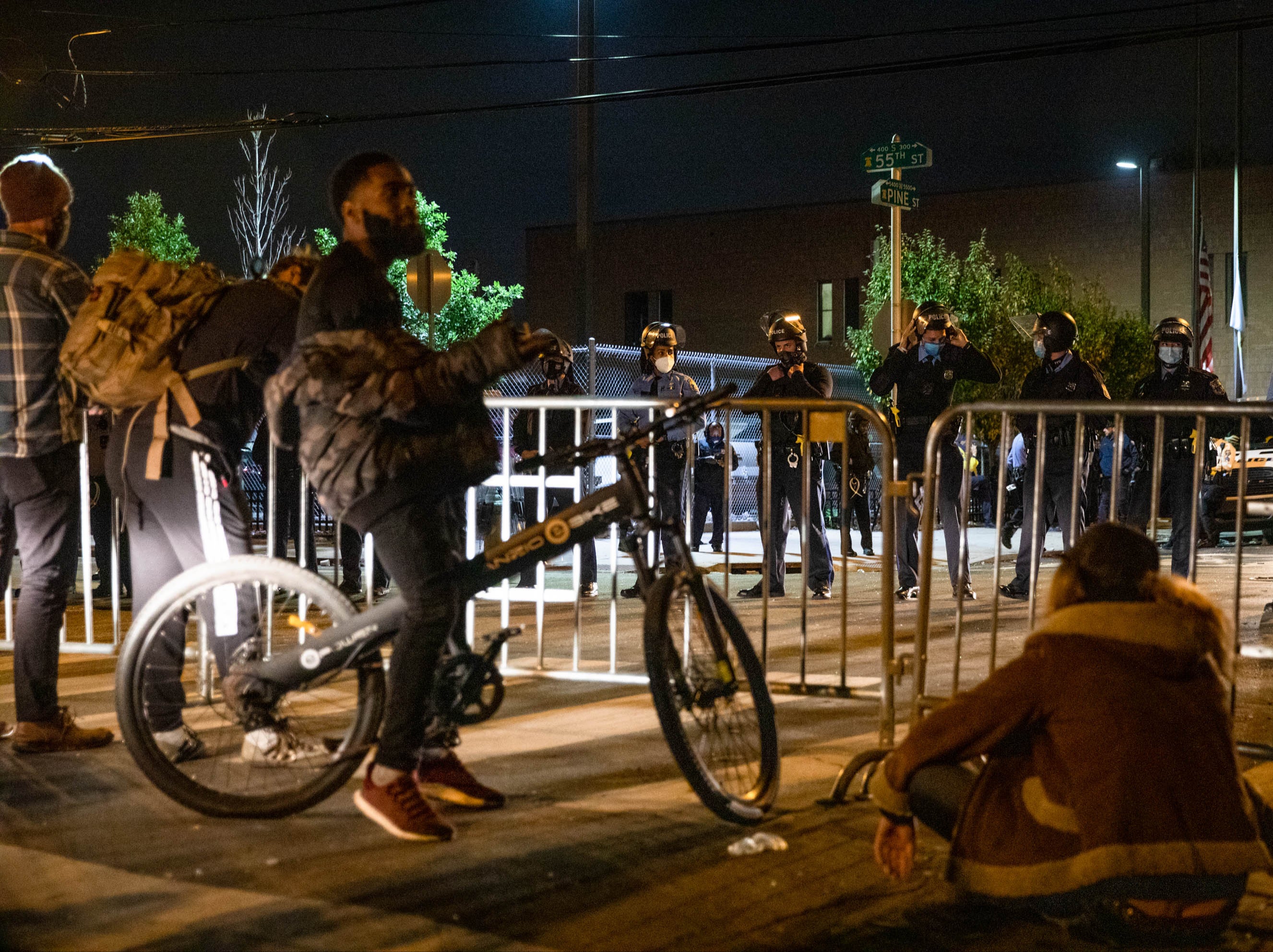 A group of protesters face police barricading the 18th Police Precinct after the city imposed a 9pm curfew in Philadelphia,