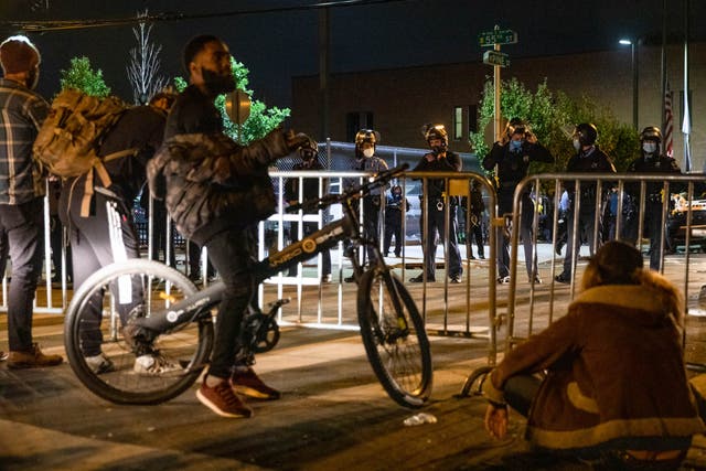 A group of protesters face police barricading the 18th Police Precinct after the city imposed a 9pm curfew in Philadelphia,