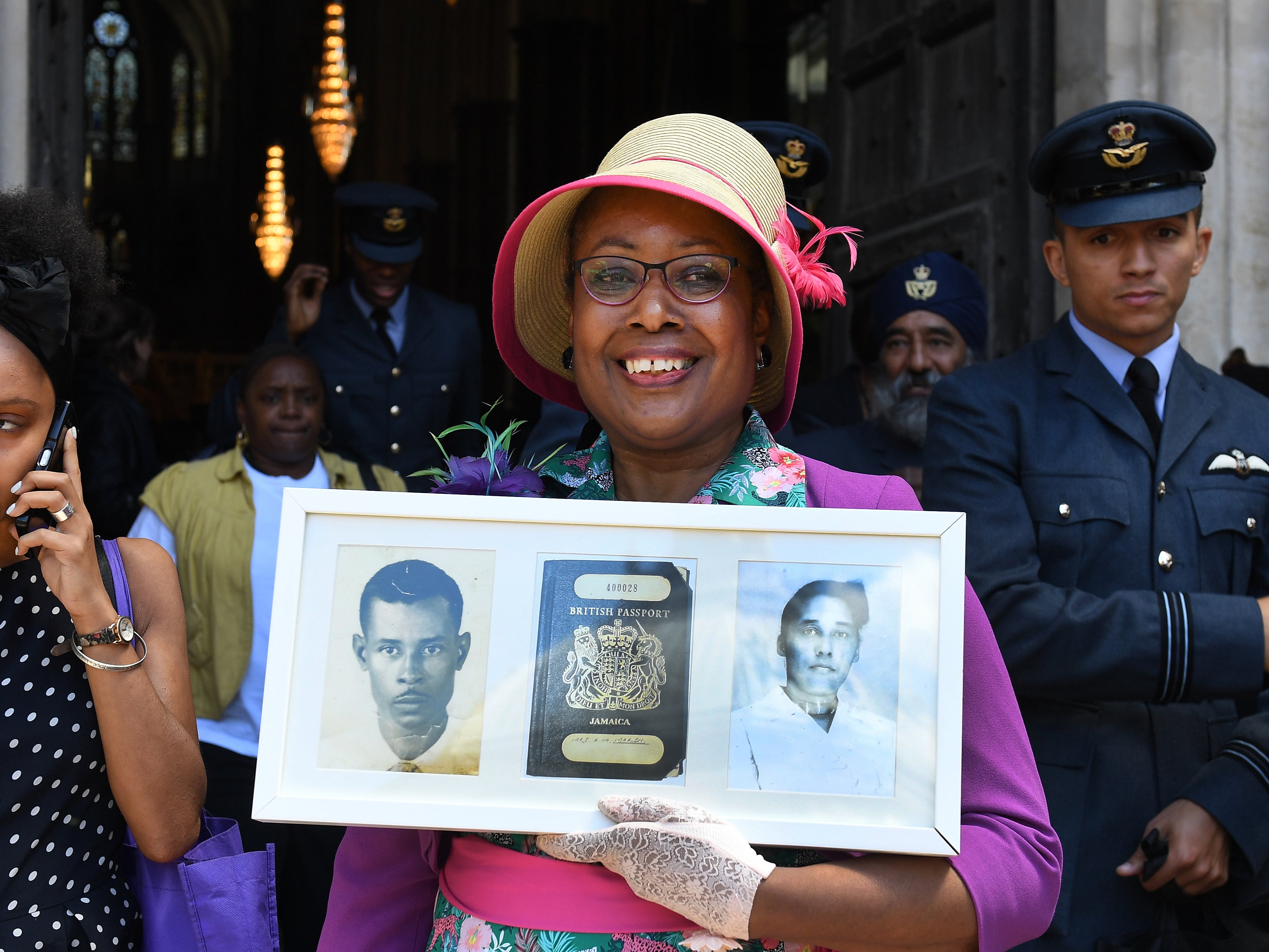 Andria Marsh holds up photographs of her parents and her original British passport after a service at Westminster Abbey in celebration of 70 years since the arrival of Empire Windrush, 22 June 2018