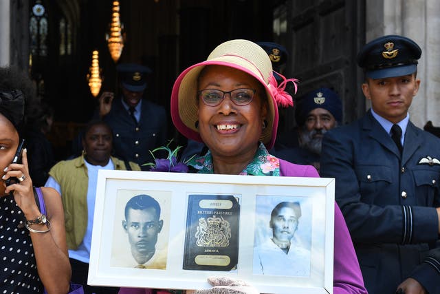 <p>Andria Marsh holds up photographs of her parents and her original British passport after a service at Westminster Abbey in celebration of 70 years since the arrival of Empire Windrush, 22 June 2018</p>