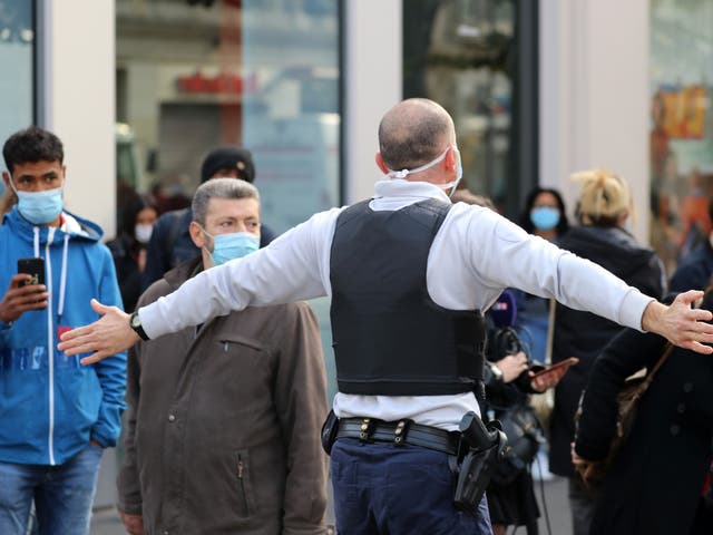 A French policeman pushes bystanders back off the street after a knife attack in Nice