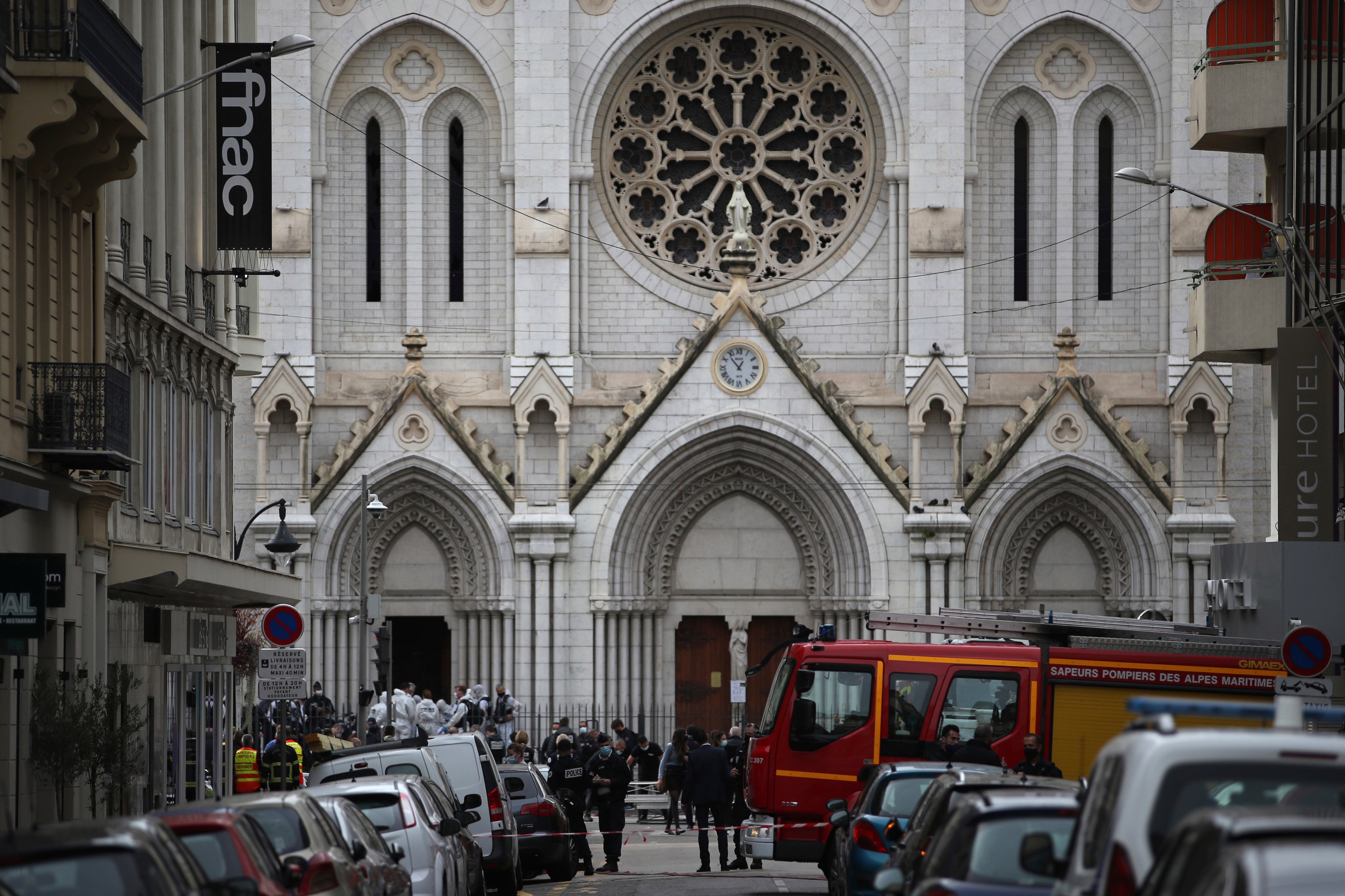 French police and forensic officers stand in front of Notre Dame church after the attack