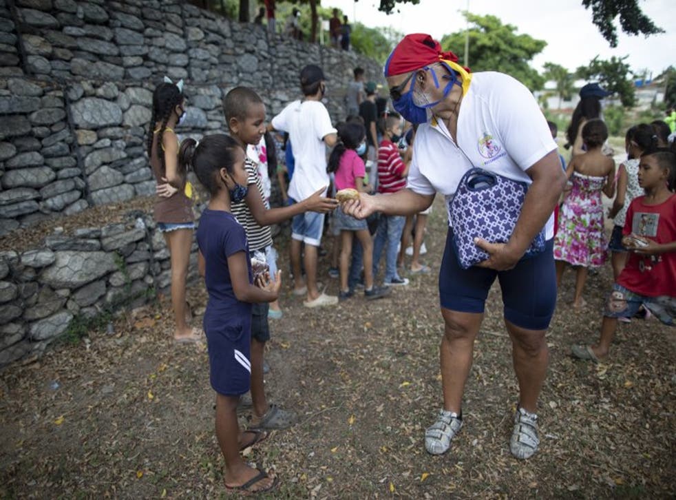 Andrés Burgos entrega un paquete de arepas caseras o empanadas de harina de maíz a un niño en Macuto, Venezuela.