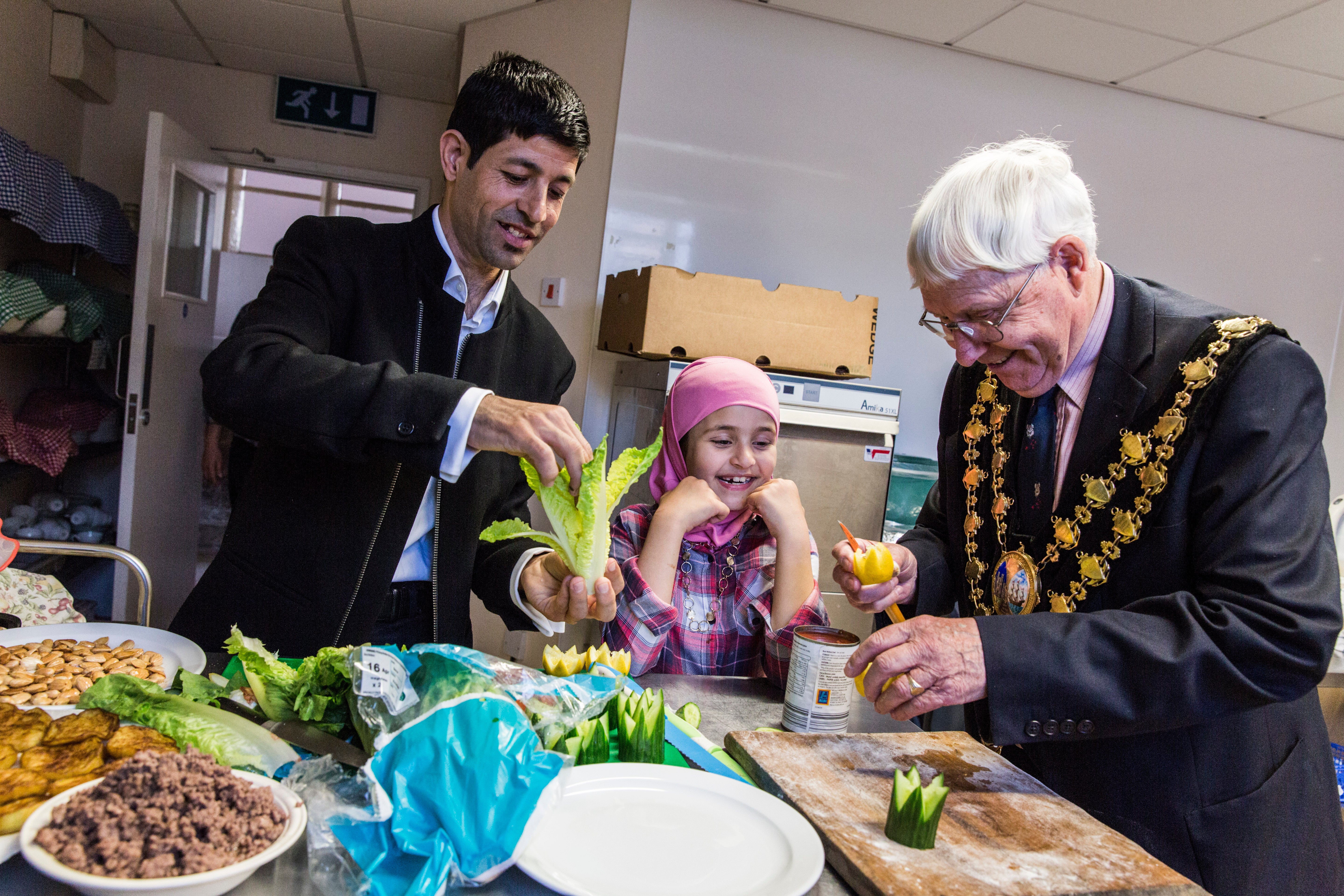 Muhaned Alchik and his daughter Sara, 8, help Mayor John Adams-Lewis to prepare Syrian food, at a church hall in Cardigan, Wales