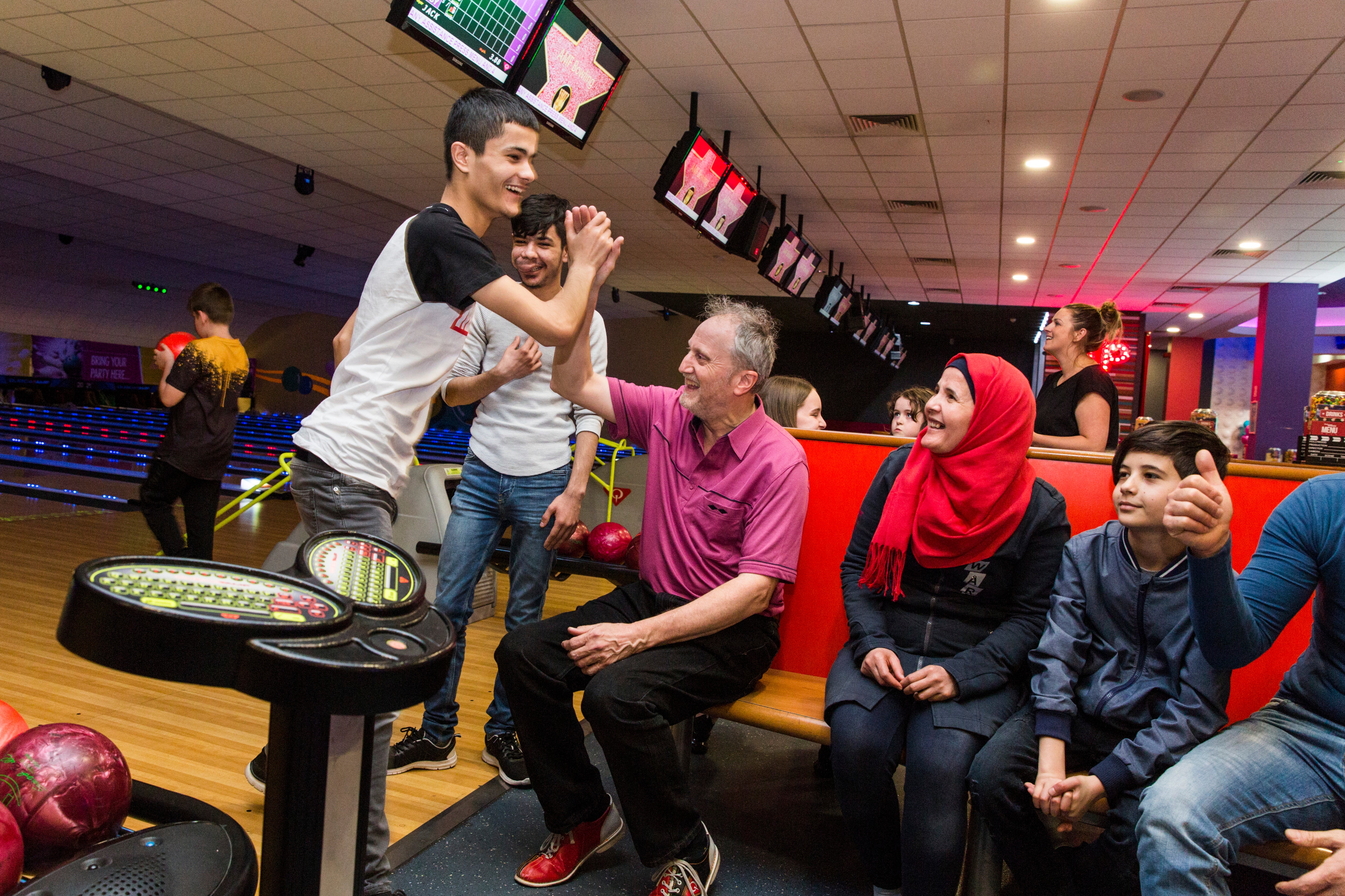 Sixteen-year-old Haitham Daour gives Ged Cavanagh a high five after a strike at a bowling alley in Bury