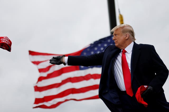 <p>President Donald Trump tosses out Make America Great Again (MAGA) caps as he arrives for a campaign rally in Michigan. REUTERS/Carlos Barria</p>