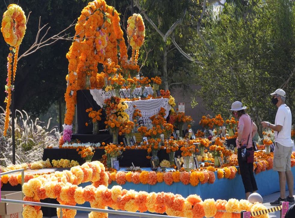 Unas personas observan una ofrenda colocada por la festividad del Día de los Muertos en Los Ángeles, el jueves 29 de octubre de 2020. (Foto/Damian Dovarganes)