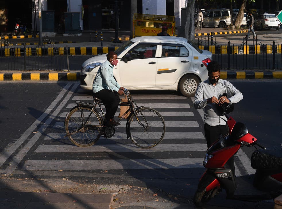 Peatones con mascarillas como medida preventiva contra el COVID-19 caminan por una carretera en Nueva Delhi.