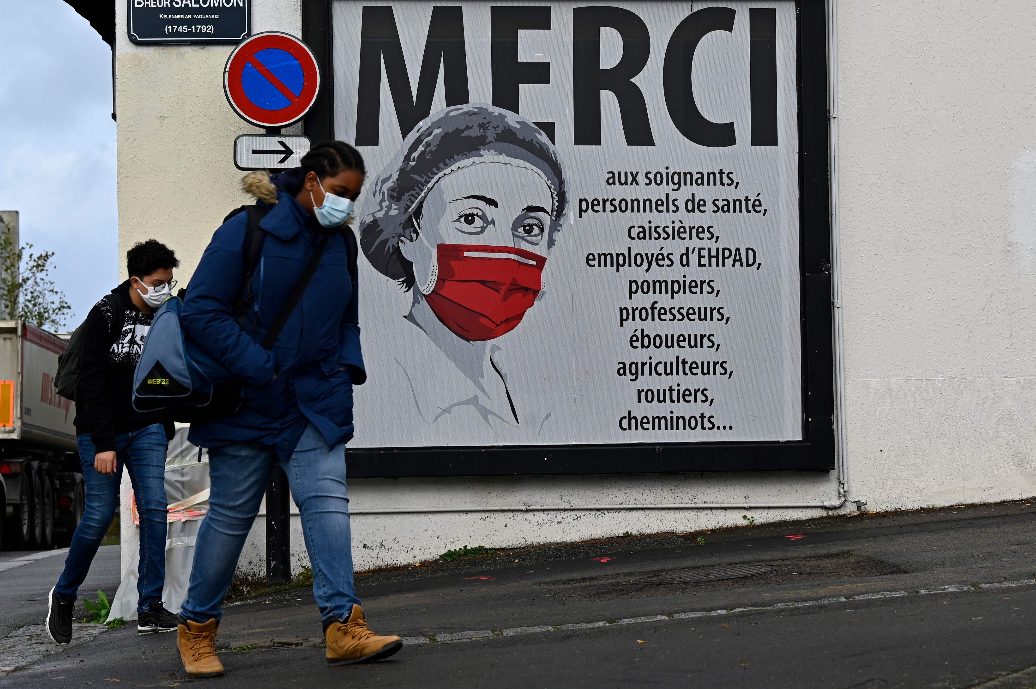 People walk past a poster featuring a nurse on a street in Rennes, western France