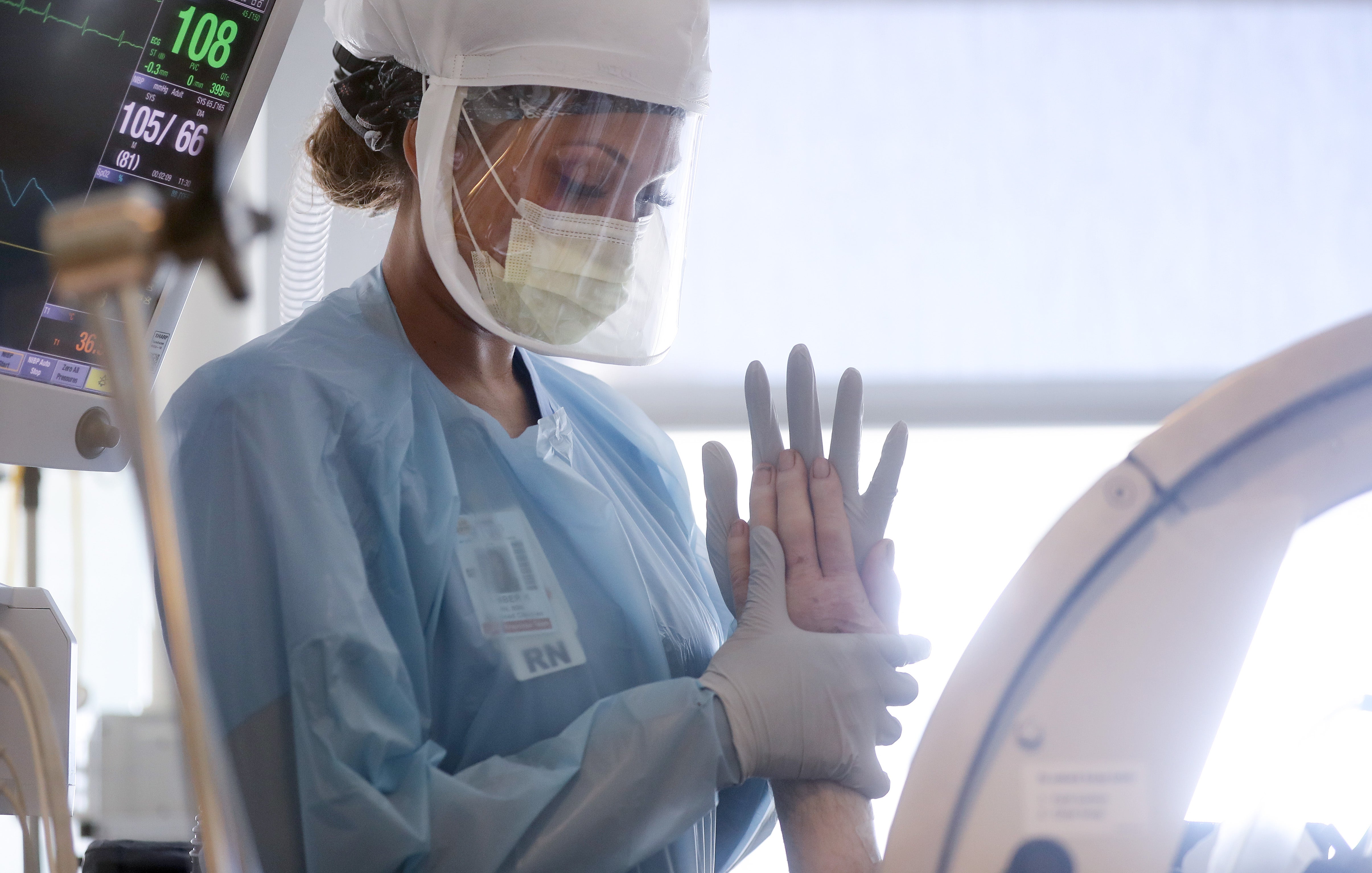 Nurse wears personal protective equipment (PPE) as she performs range of motion exercises on a COVID-19 patient
