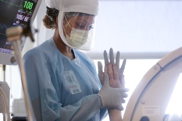 <p>Nurse wears personal protective equipment (PPE) as she performs range of motion exercises on a COVID-19 patient</p>