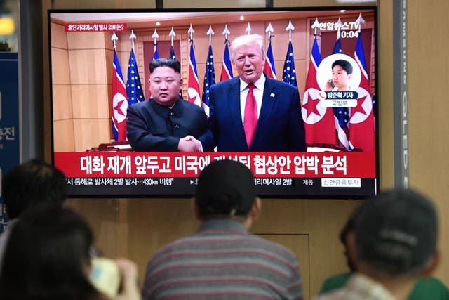 People watch a television news showing a file footage of a meeting between US President Donald Trump and North Korean leader Kim Jong Un