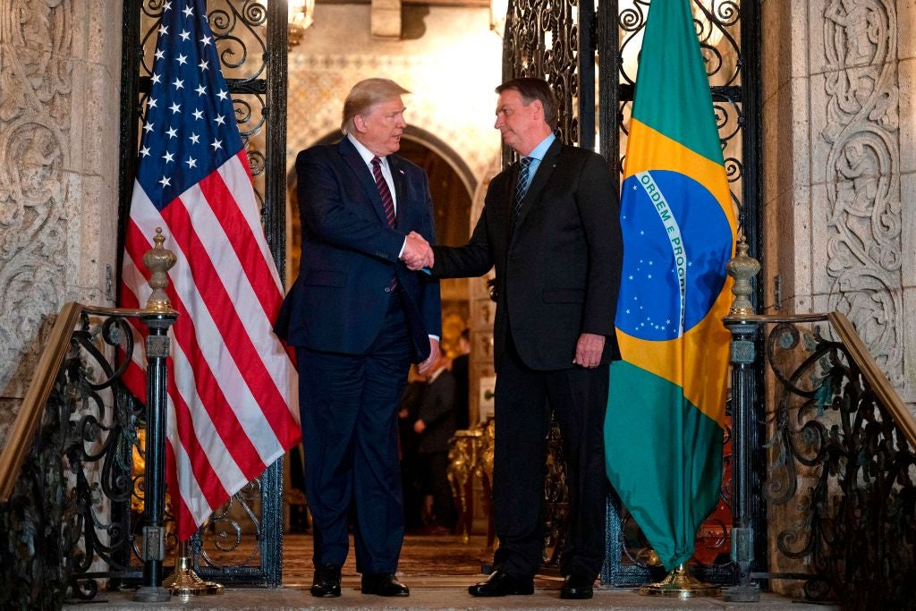 US President Donald Trump (L) shakes hands with Brazilian President Jair Bolsonaro during a diner at Mar-a-Lago in Palm Beach, Florida