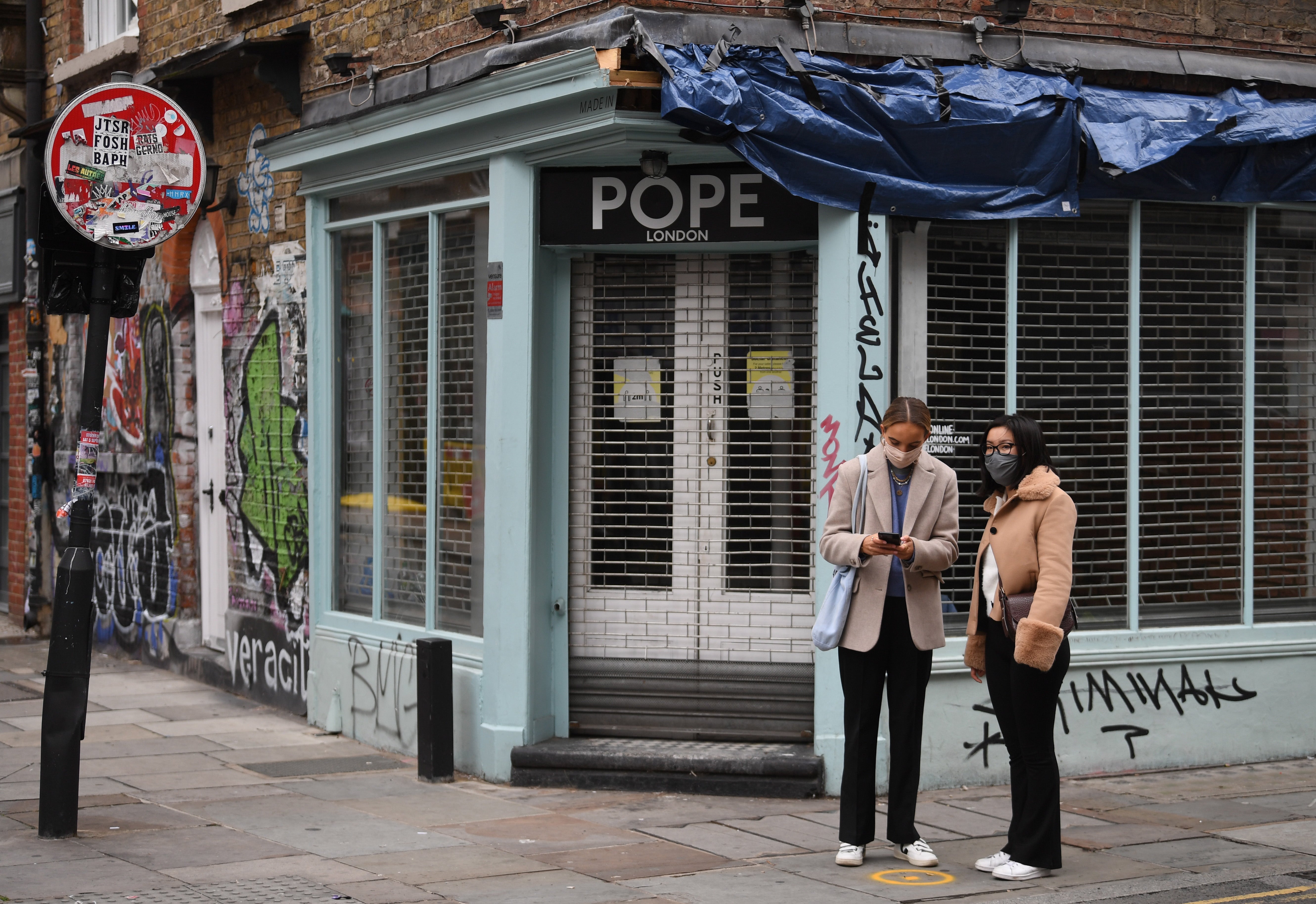 Masked people pass a closed shop in London last month