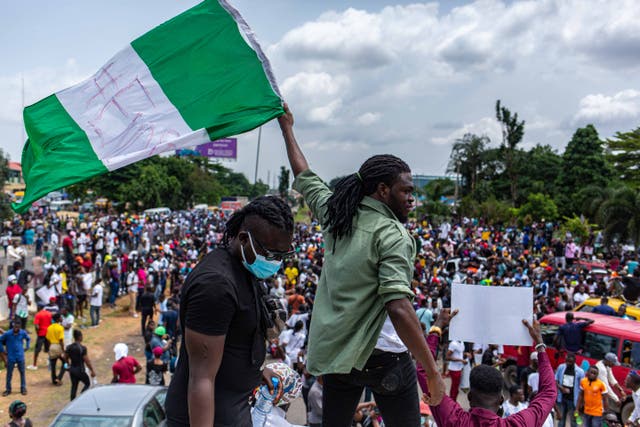 <p>A Nigerian man waves the national flag in support of the ongoing protest against the brutality of the Special Anti-Robbery Squad (SARS) in Lagos</p>