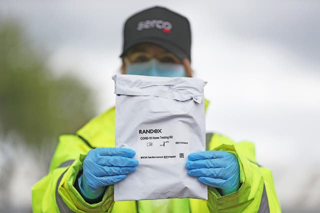 A member of the testing staff holds a Randox laboratories Covid-19 self test kit at a drive-through test centre at the SSE Arena in Belfast.