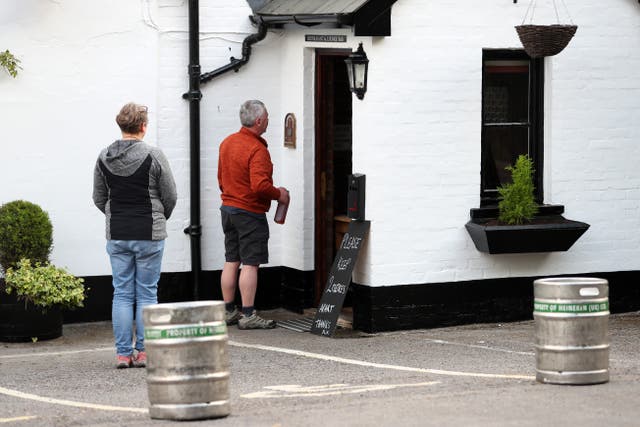 Drinkers queue for takeaway beer at a pub during the first lockdown