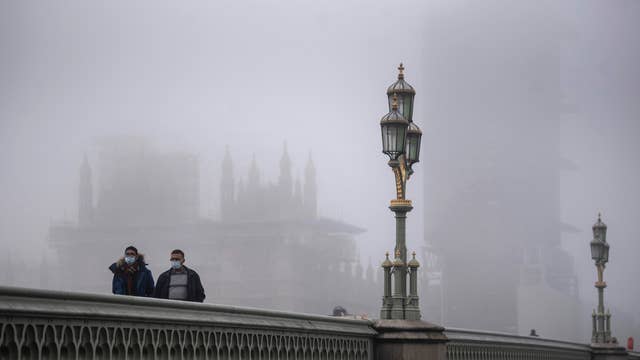Hai người đàn ông đi bộ qua cầu Westminster gần như vắng vẻ, trong điều kiện sương mù, khi bắt đầu cuộc cấm vận quốc gia kéo dài 4 tuần đối với Anh