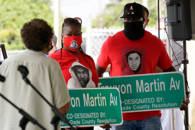 <p>Sybrina Fulton, center and Tracy Martin, parents of Trayvon Martin, hold street signs with their son's name, Thursday, Nov. 5, 2020, in Miami Gardens, Fla. The street on the way to Martin's former school was renamed in his honor, eight years after he was killed by a neighborhood watch volunteer in Sanford, Fla. </p>