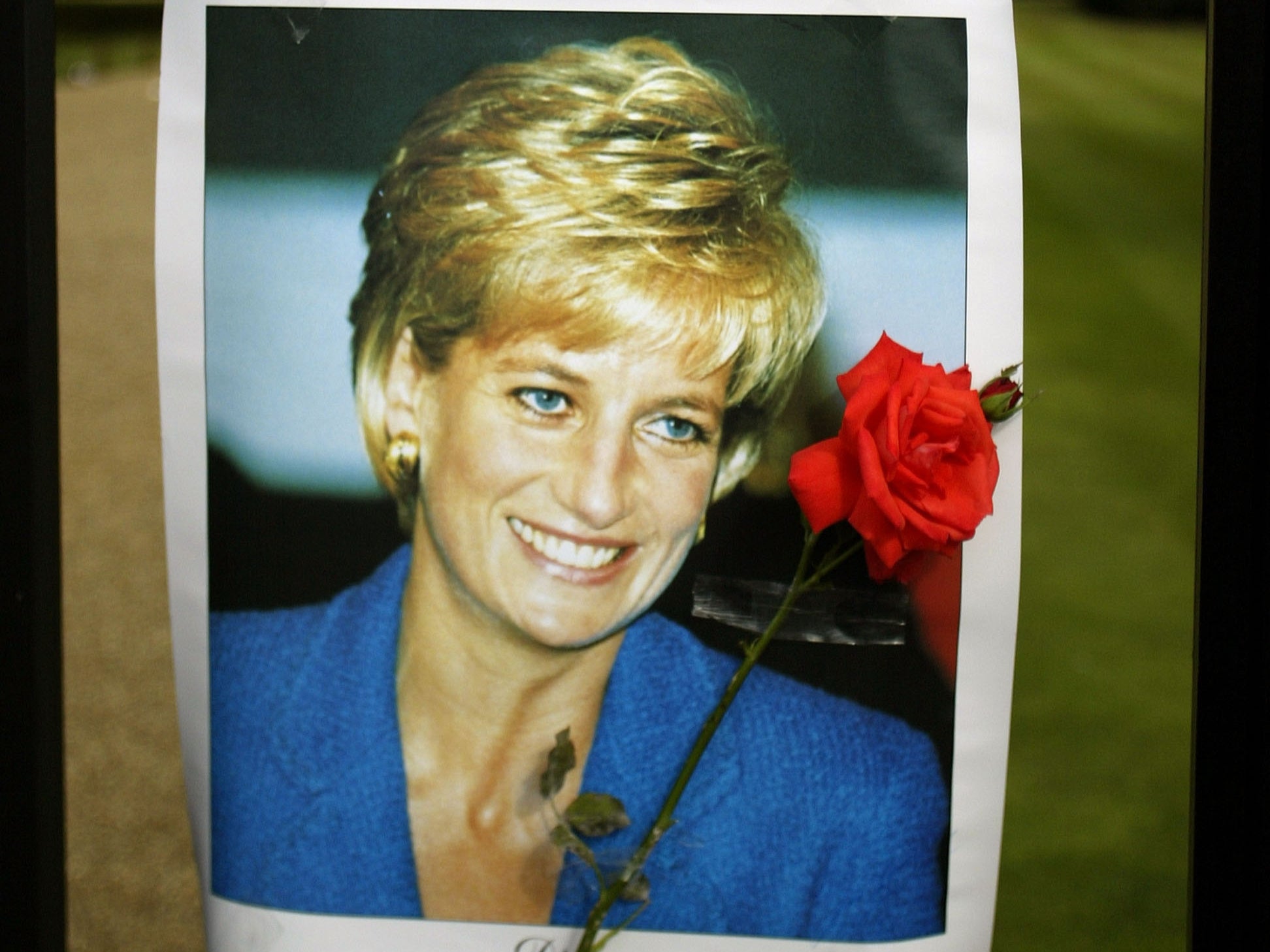 A red rose and photograph of Princess Diana on the gates of Kensington Palace