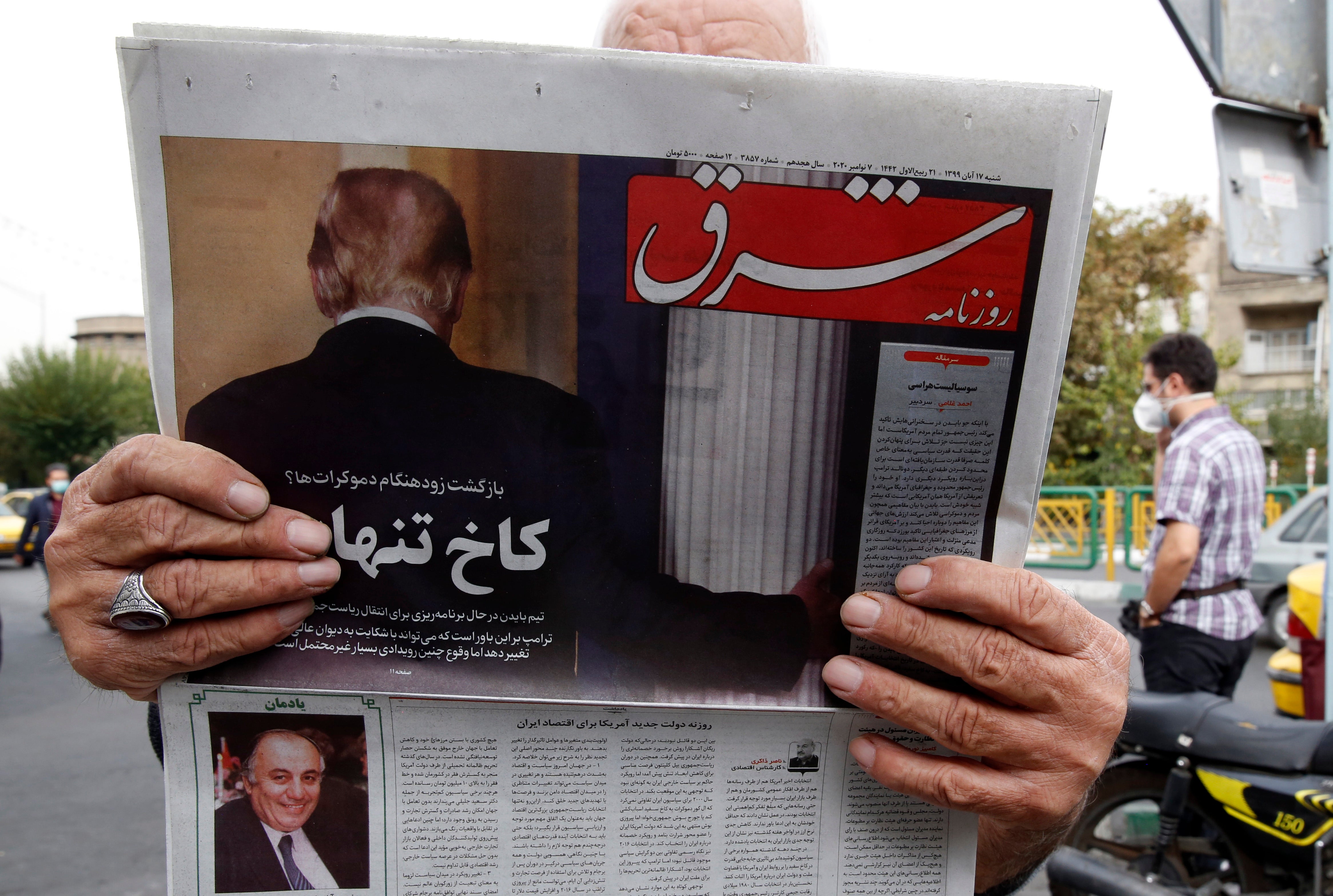 A man reads a copy of Iranian daily newspaper ‘Shargh’ with a picture of outgoing US president Donald Trump