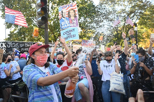 A woman sprays prosecco onto the crowd as people celebrate on Black Lives Matter plaza across from the White House in Washington, DC on November 7, 2020, after Joe Biden was declared the winner of the 2020 presidential election. - Democrat Joe Biden has won the White House, US media said November 7, defeating Donald Trump and ending a presidency that convulsed American politics, shocked the world and left the United States more divided than at any time in decades. (Photo by MANDEL NGAN / AFP) (Photo by MANDEL NGAN/AFP via Getty Images)