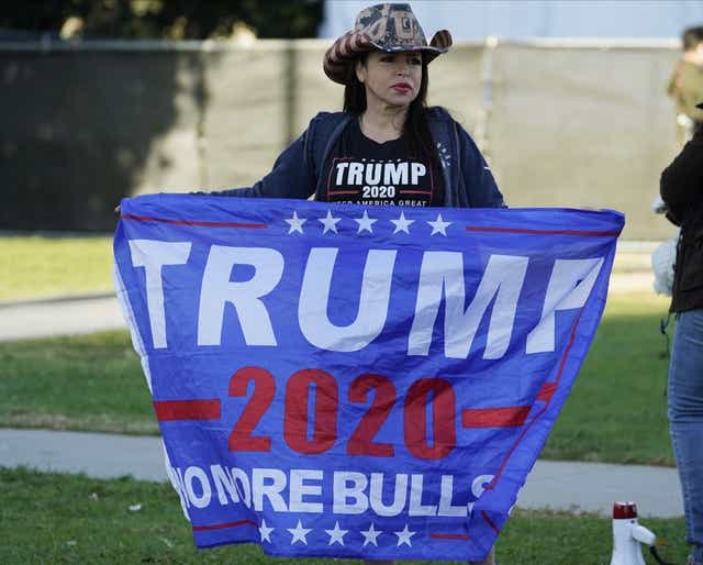 Una partidaria de la reelección de Donald Trump como presidente de Estados Unidos sostiene una bandera, amnifestándose en el norte del Bulevar de Santa Mónica, en Beverly Hills, California...
