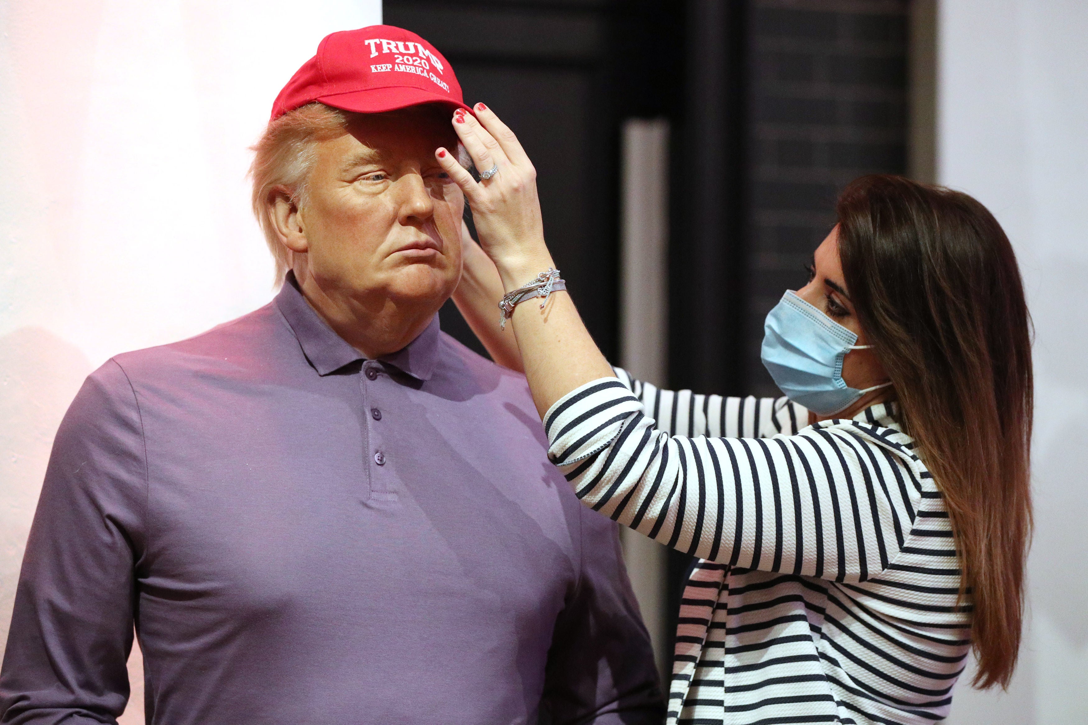 A member of the Madame Tussauds studios team adjusts a wax figure of Donald Trump which has been re-dressed in golf wear following the 2020 US presidential election