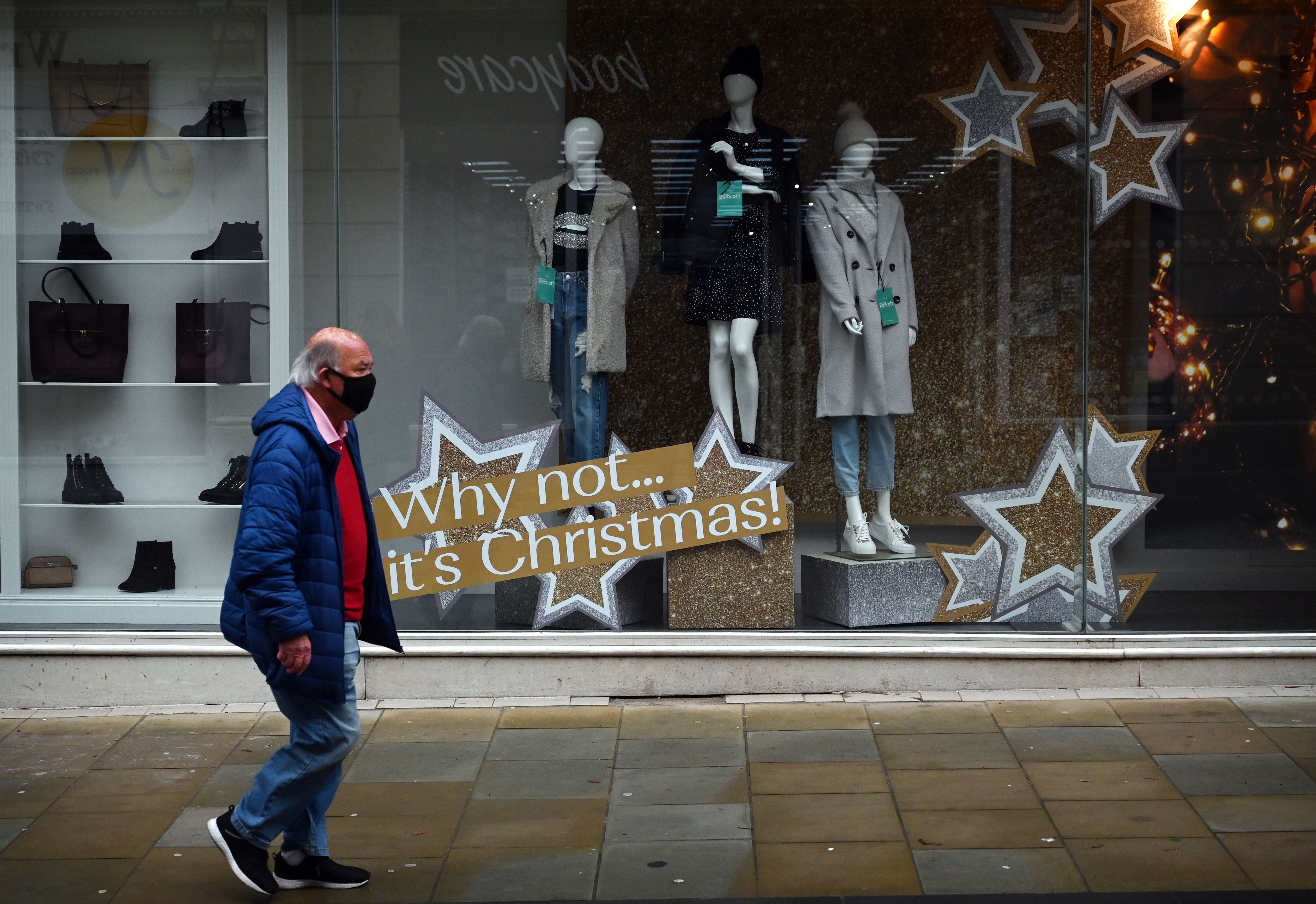 A pedestrian walks past a shop with a Christmas display