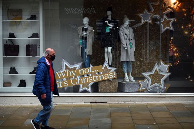 A pedestrian walks past a shop with a Christmas display