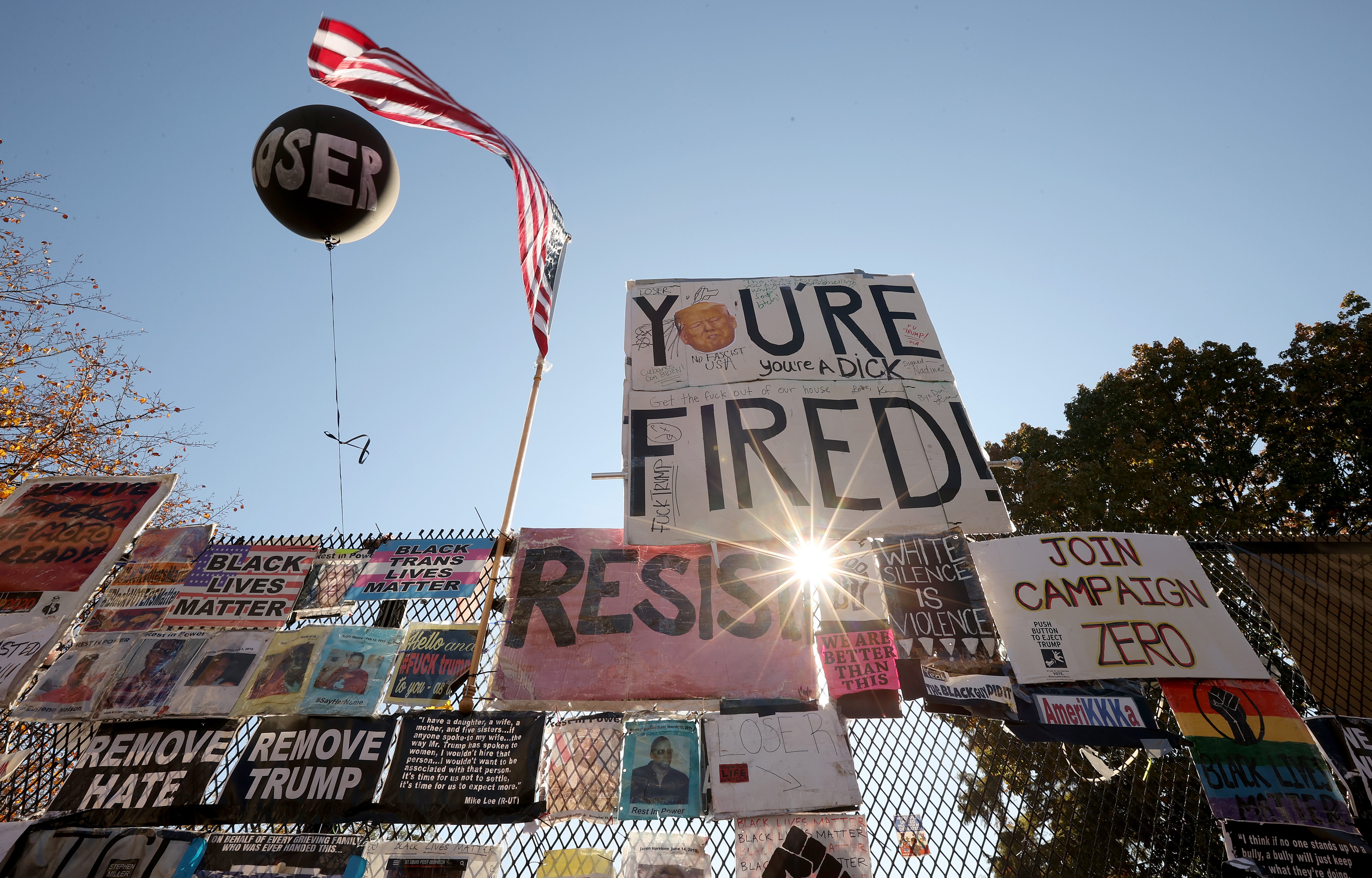 Signs critical of President Donald Trump hang on White House fence