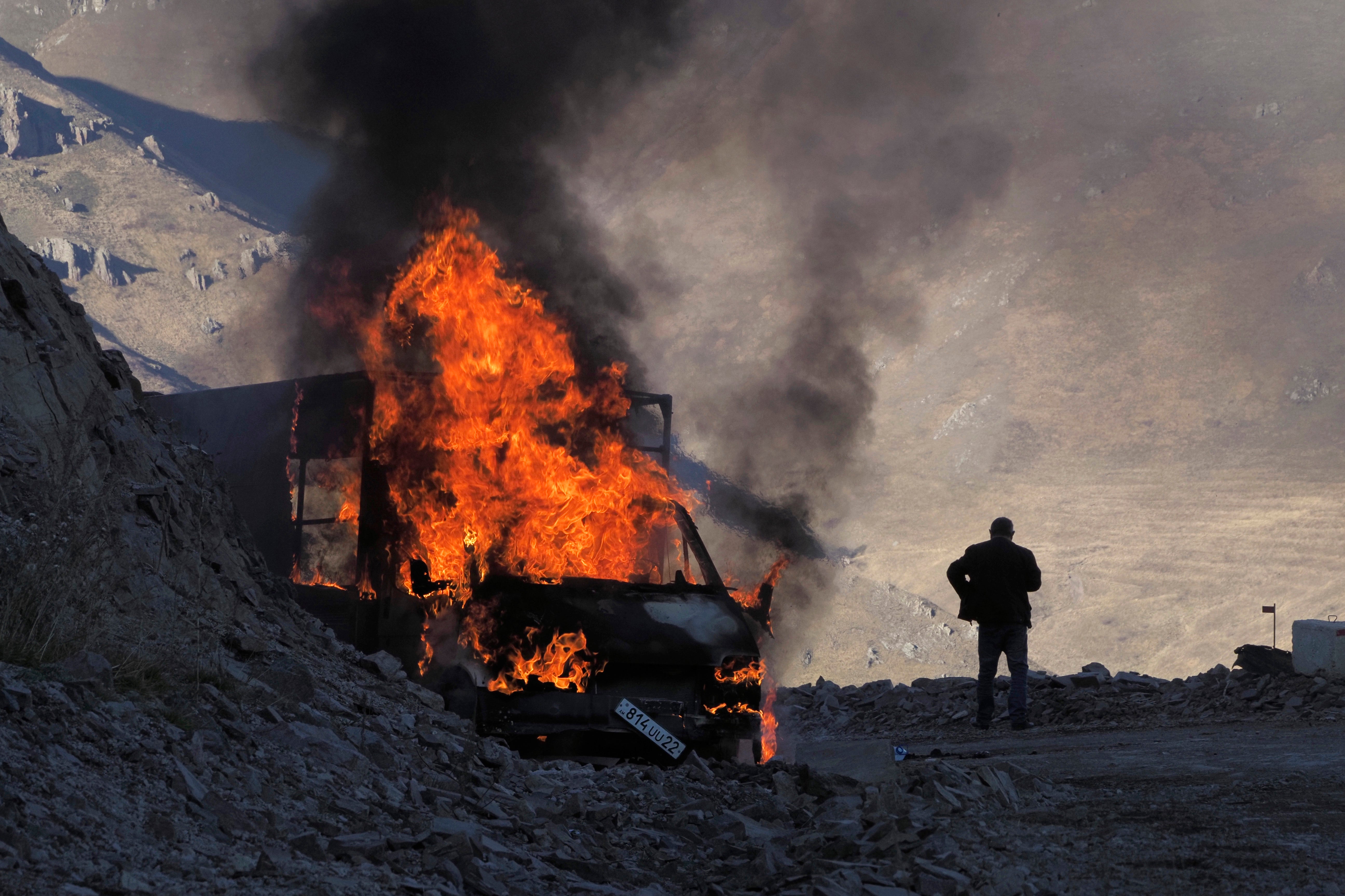 A man stands near his burning car which caught on fire along the road to a mountain pass, near the border between Nagorno-Karabakh and Armenia