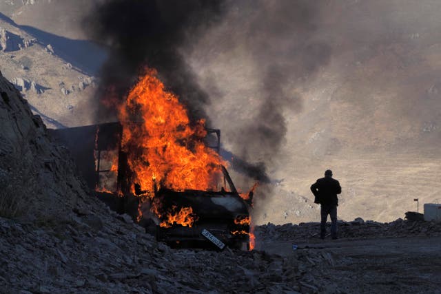 <p>A man stands near his burning car which caught on fire along the road to a mountain pass, near the border between Nagorno-Karabakh and Armenia</p>
