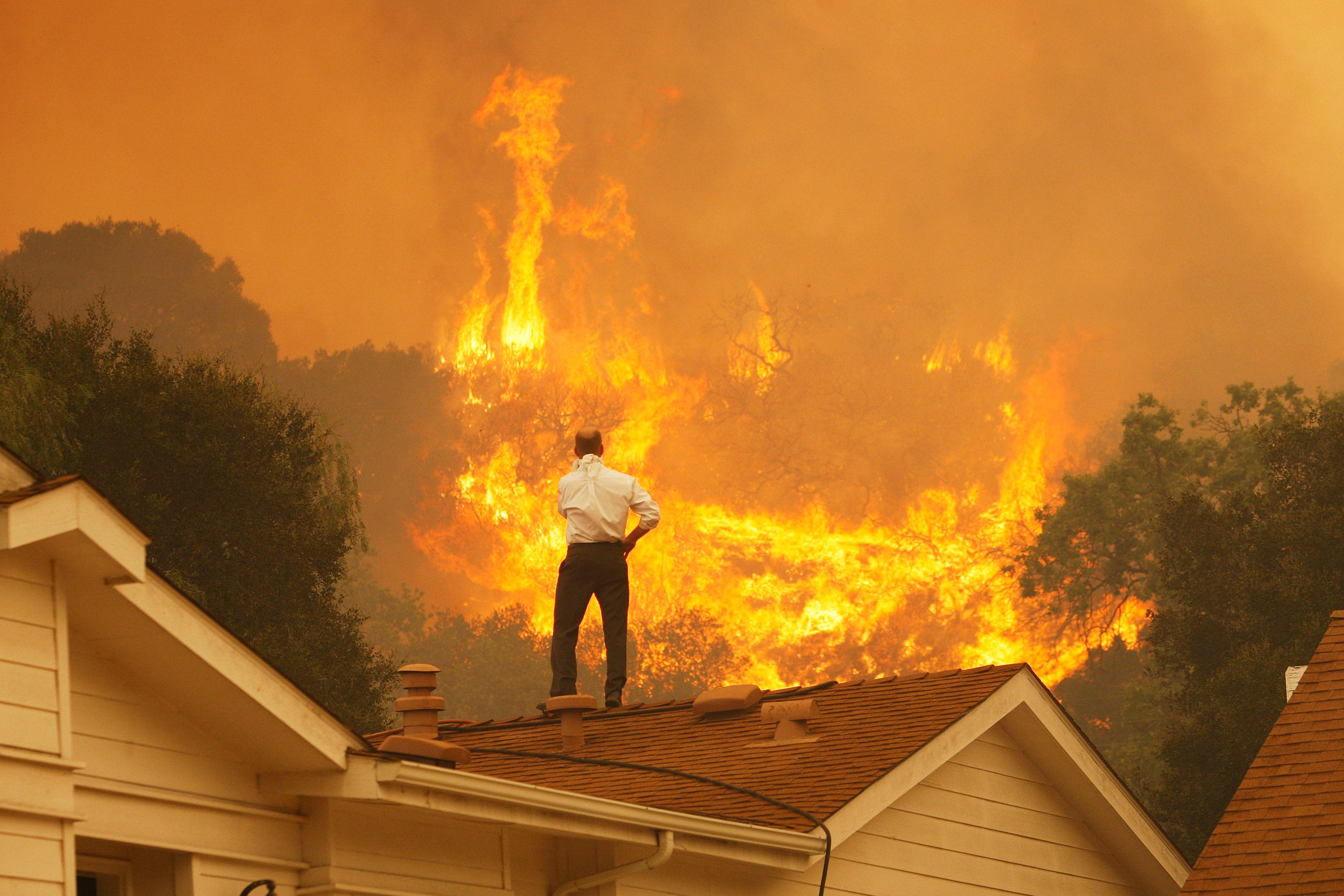 A man on a rooftop looks at approaching flames near Camarillo, California. The president-elect has promised to put climate action at the heart of his agenda for the next four years