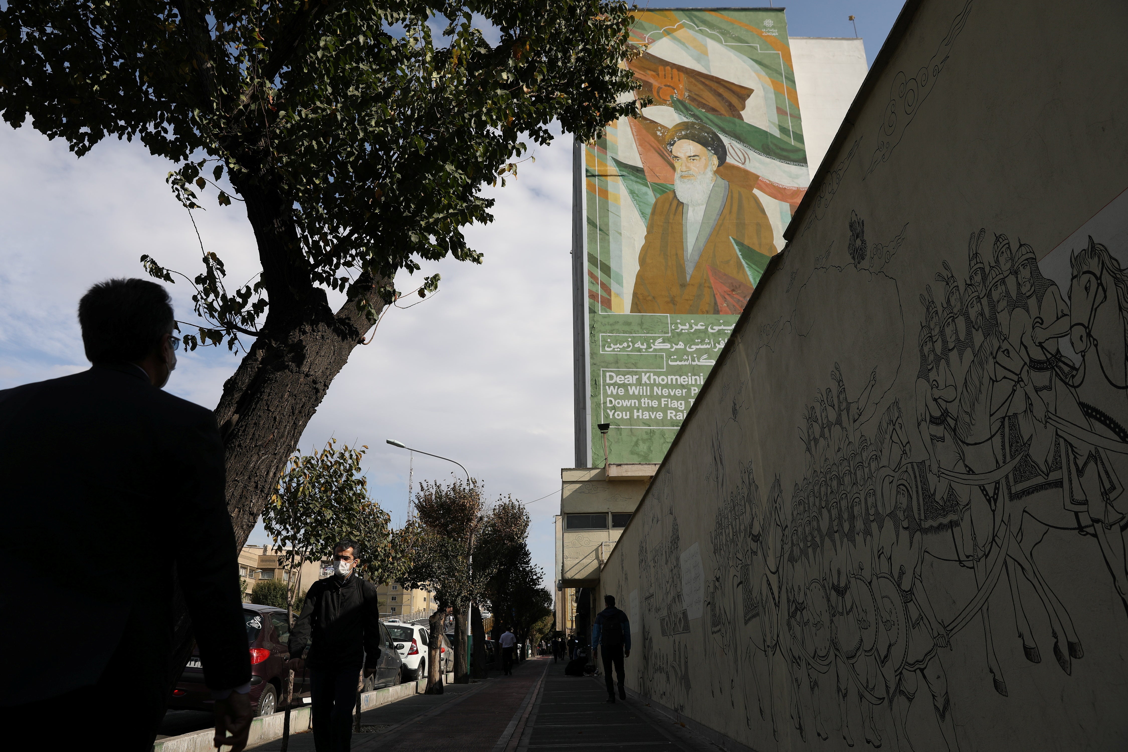 People walk on a pavement as a banner depicting Iran’s late leader Ayatollah Ruhollah Khomeini. Majid Asgaripour/WANA (West Asia News Agency) via REUTERS ATTENTION EDITORS