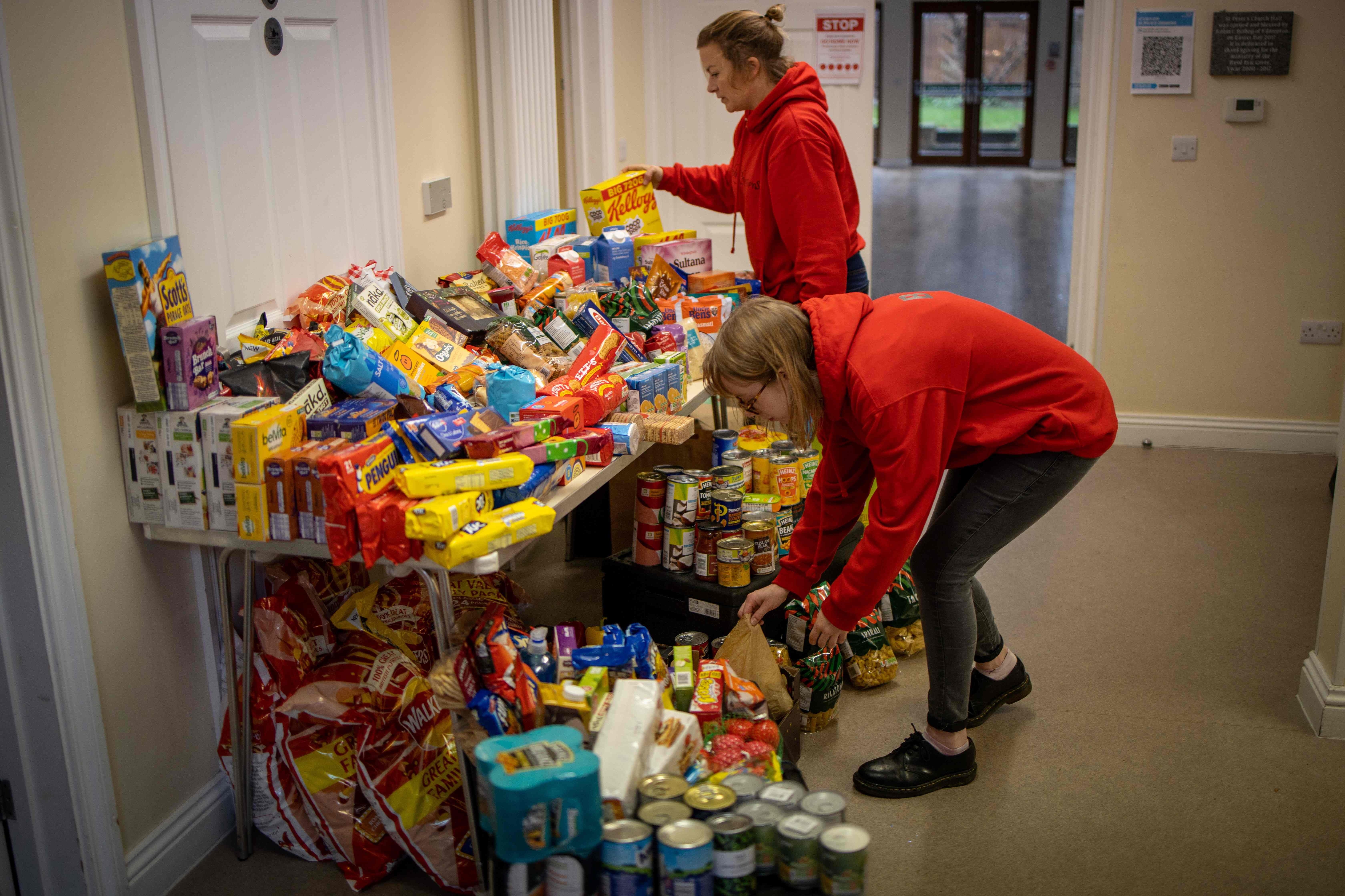 <p>Staff organise food donations for families at the Cooking Champions food bank in Grange Park, London</p>