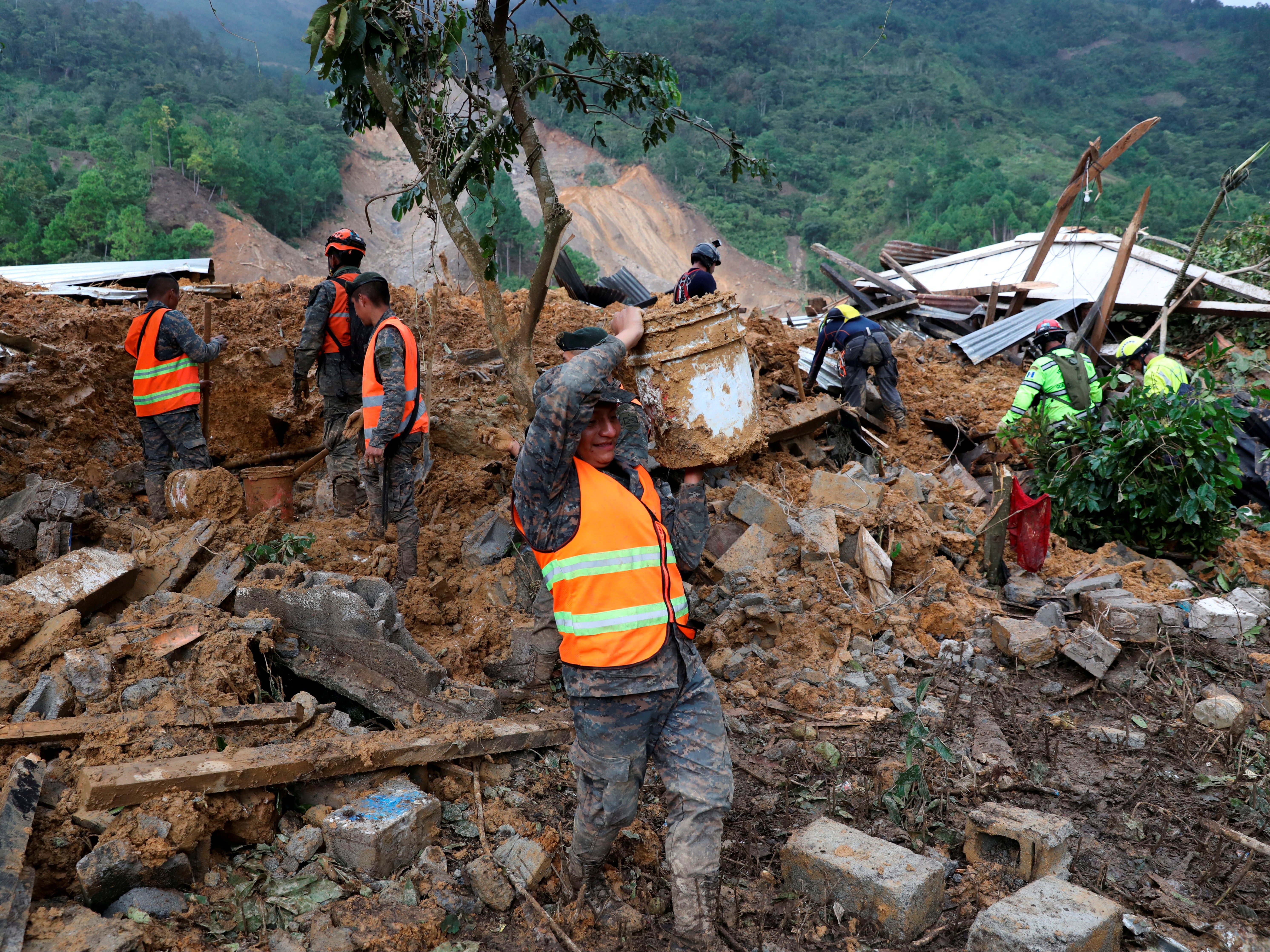 Soldiers remove debris and mud from an area hit by a mudslide, caused by heavy rains brought by Storm Eta