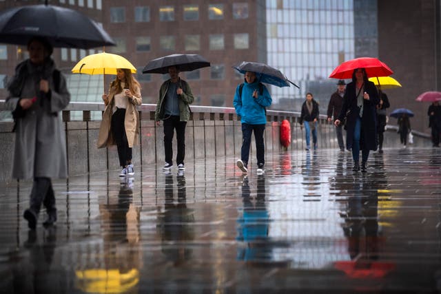 Commuters are pictured crossing London Bridge in the rain on 21 October, 2020. 