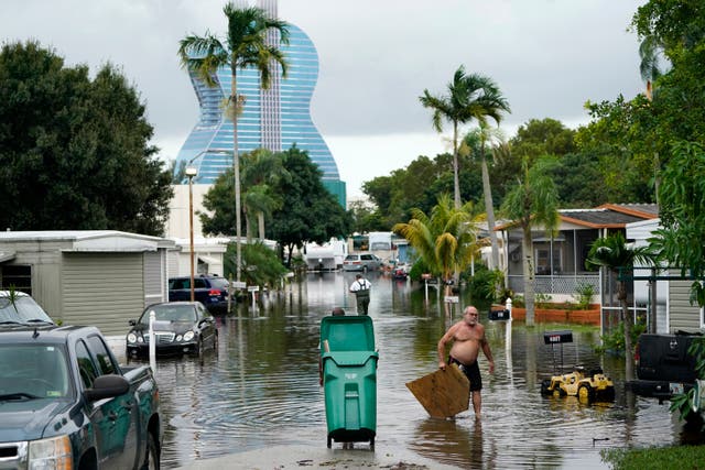 Residents clear debris from a flooded street in the Driftwood Acres Mobile Home Park in the shadow of the Guitar Hotel at Seminole Hard Rock, in the aftermath of Tropical Storm Eta on Tuesday