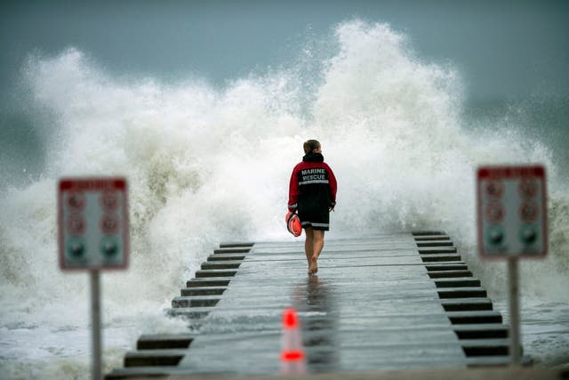 Un salvavidas camina hasta el final del embarcadero después de cerrarlo a los surfistas antes de la llegada de la tormenta tropical Eta en Bradenton Beach, Florida