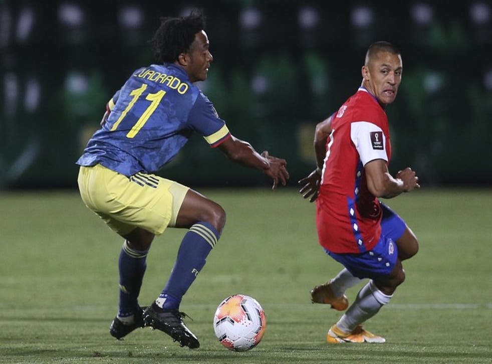 El delantero chileno Alexis Sánchez, derecha, busca el balón ante la marca del colombiano Juan Cuadrado, durante un partido por las eliminatorias sudamericanas para el Mundial Qatar 2022, en el Estadio Nacional Julio Martínez Prádanos, en in Santiago, Chile, el martes 13 de octubre de 2020.