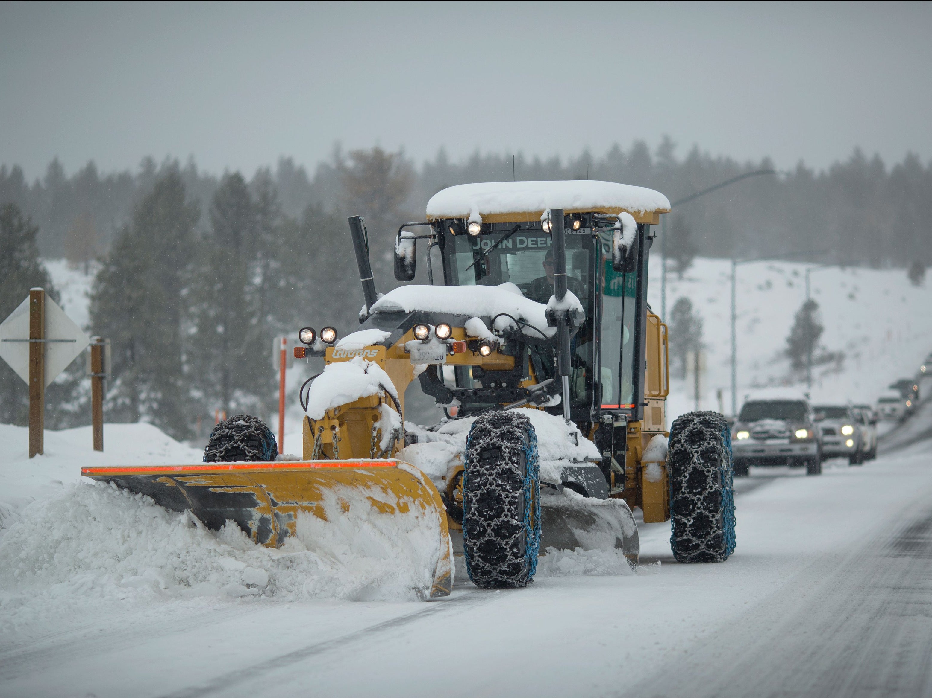 A line of cars follows a tractor plowing snow near Mammoth Lakes, California on 9 January 2017
