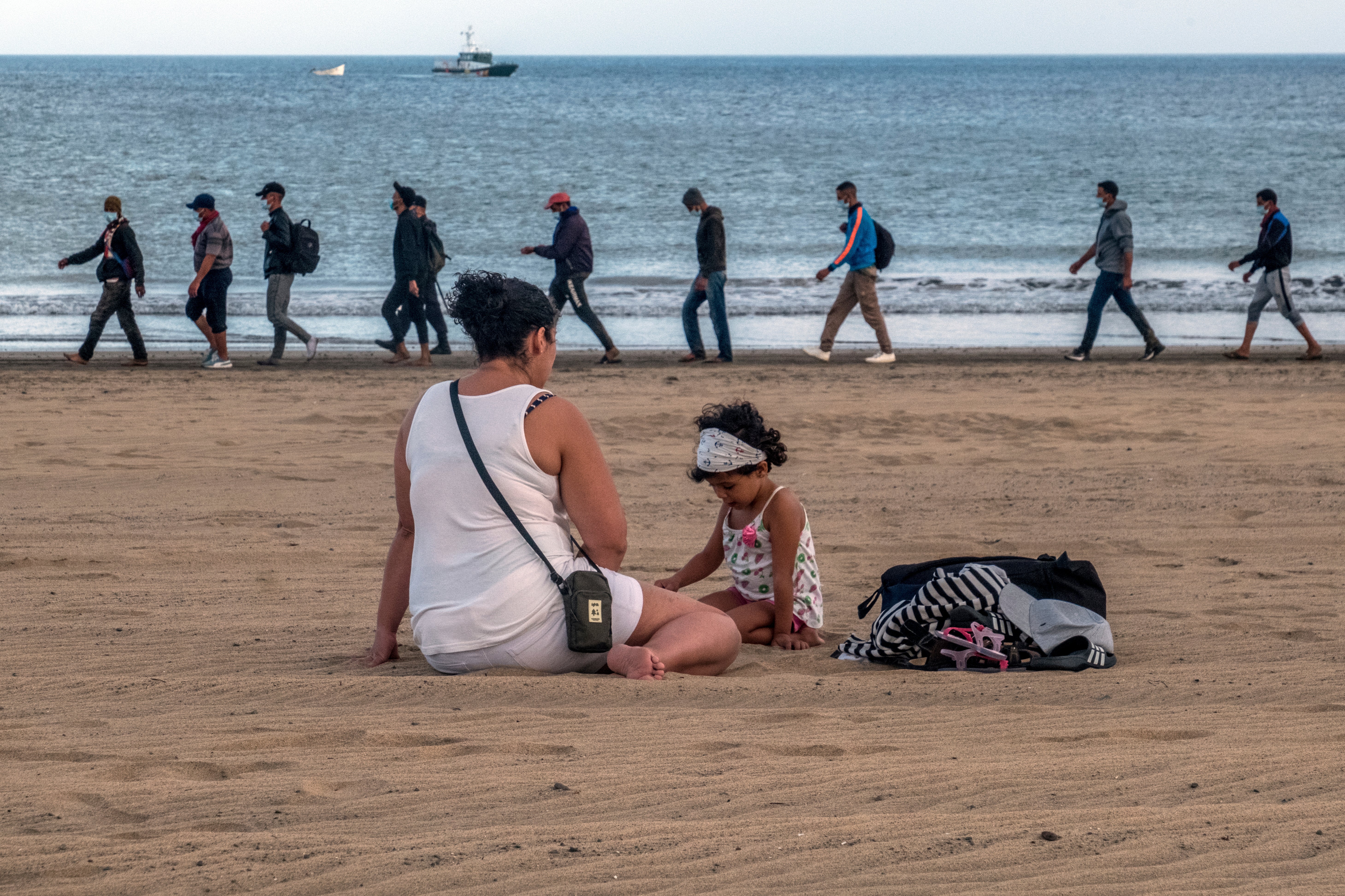 Migrants from Morocco walk along the shore escorted by Spanish police after arriving on Gran Canaria