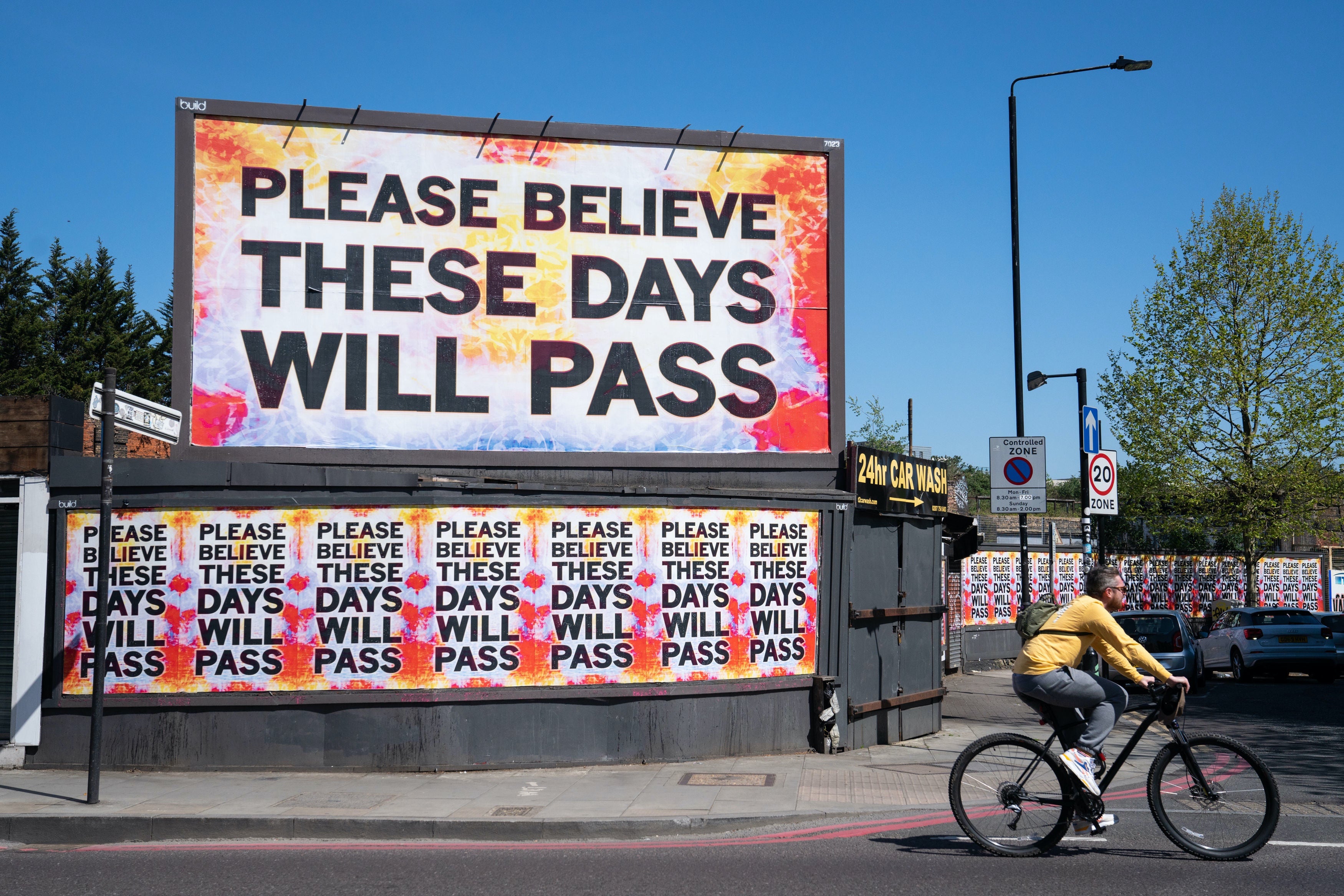 Cyclist rides past east London billboard