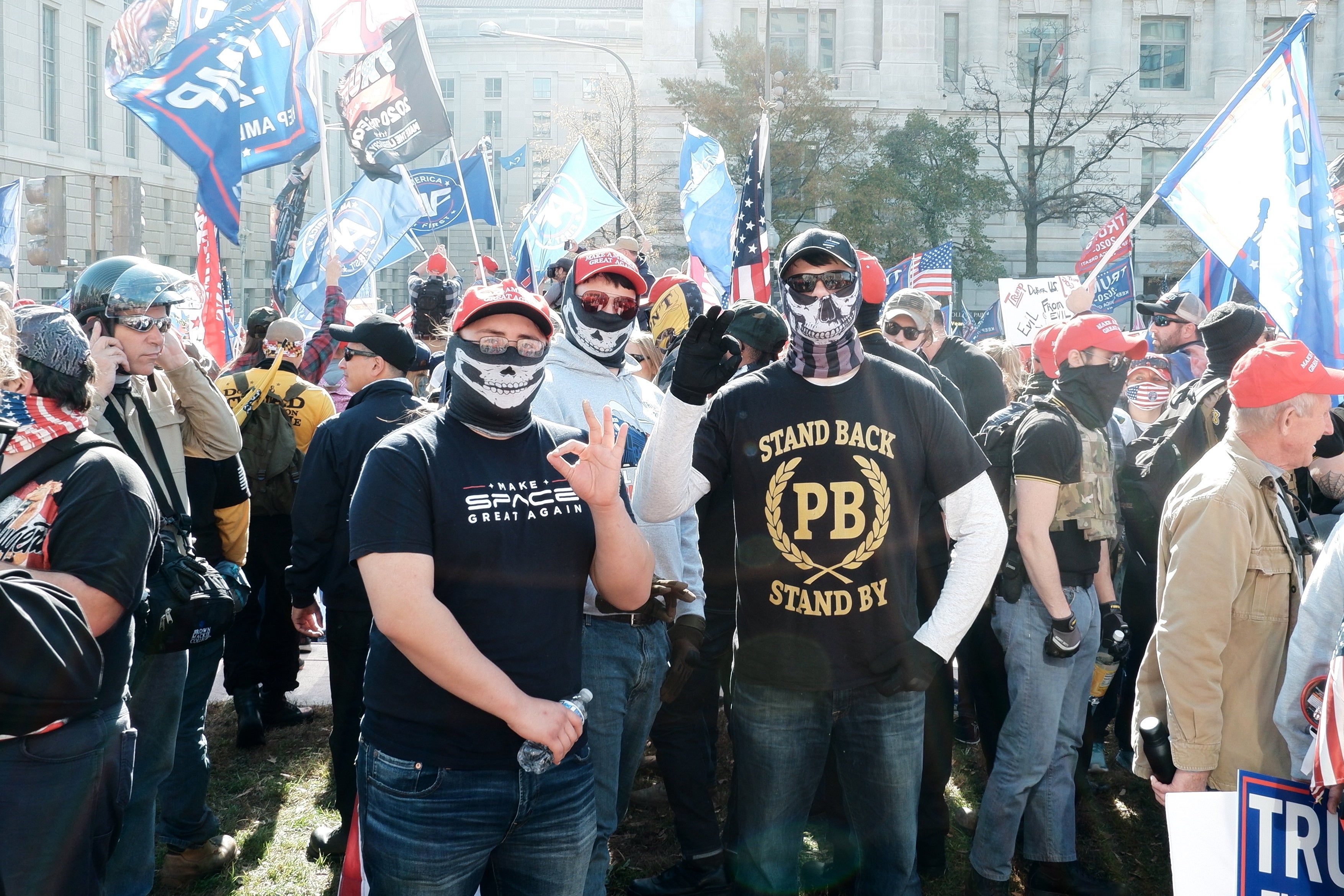 Two people, one of them with a Proud Boys shirt, gesture with the White Power sign, as supporters of Trump gather in Freedom Plaza, in Washington, DC